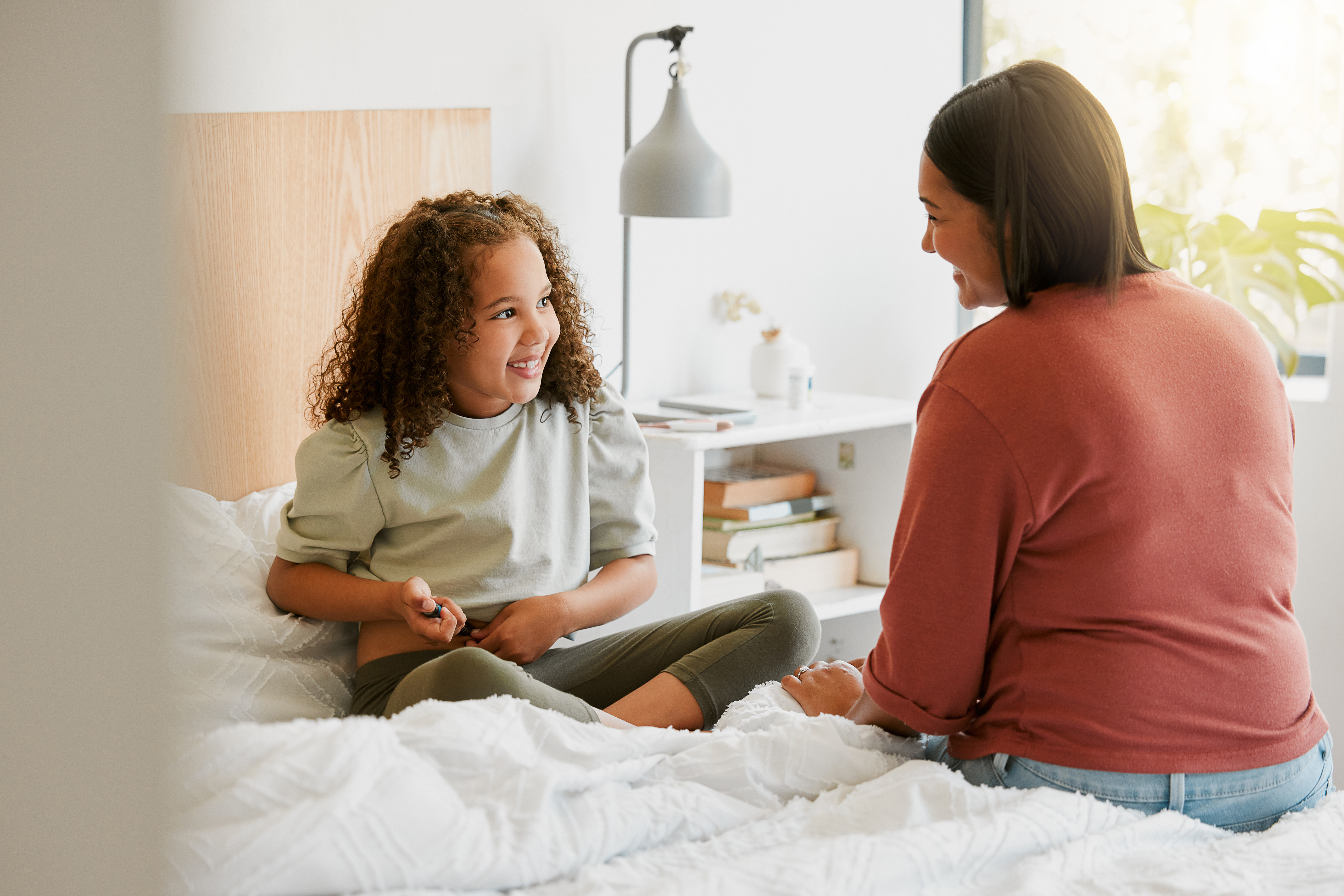 Caring mother teaching child to take insulin injection by herself looking happy, proud and brave at home. Little girl injecting self with blood sugar measuring device to test for chronic illness