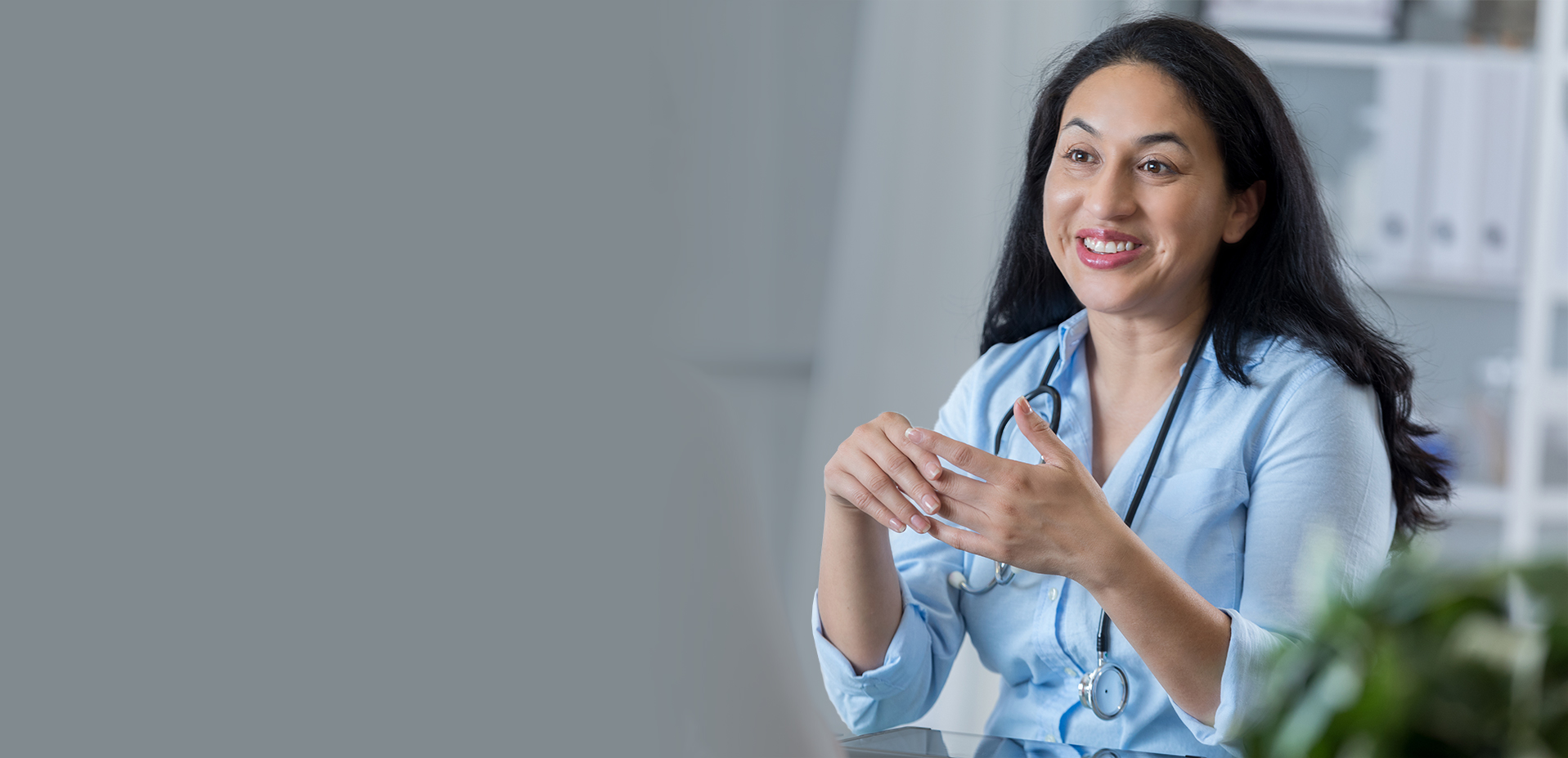 An adult female doctor sits across from her unrecognizable patient.
